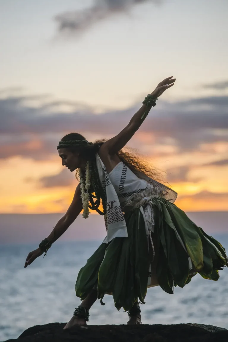 Hula dancer on coastal rocks at sunset
