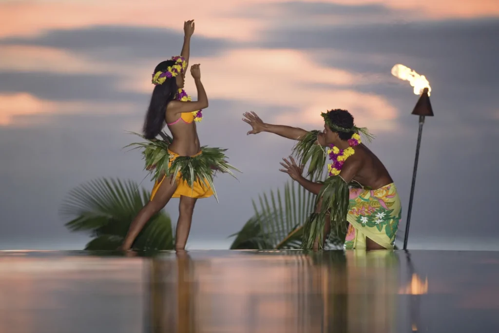 Two hula dancers performing beside the ocean at sunset