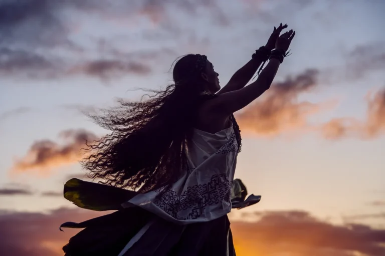 Hula dancer silhouetted against a sunset sky